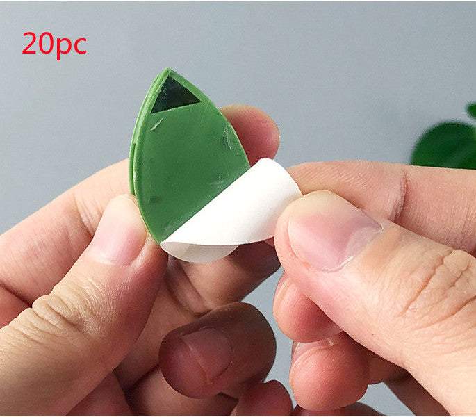Green self-adhesive plant fixture clip shaped like a leaf for supporting climbing plants on walls