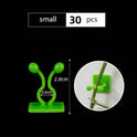 Green leaf-shaped self-adhesive plant fixture clip holding climbing plant on wall